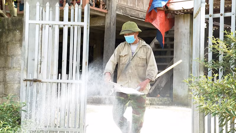 Người dân tiến hành rắc vôi khử trùng khu vực xung quanh nhà ở theo hướng dẫn.