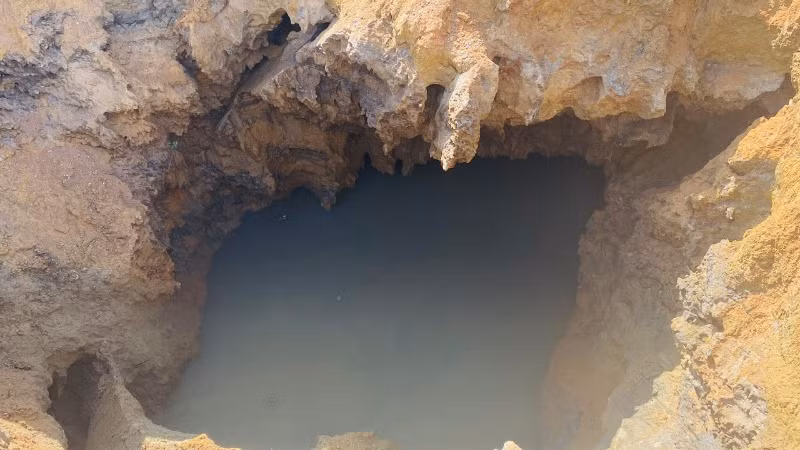 Nước ngầm đùn ra theo hàm ếch dưới đáy hố sụt. (Ảnh: TUẤN SƠN)