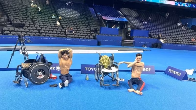 Vận động viên bơi lội Đỗ Thanh Hải và Lê Tiến Đạt khởi động trước khi xuống bể tập. (Ảnh: TTXVN)