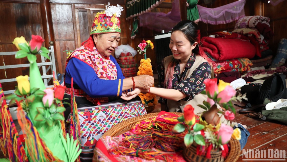 Nghệ nhân người Lào ở xã Núa Ngam, huyện Điện Biên thực hiện nghi thức văn hóa buộc chỉ cổ tay cầu may cho du khách.