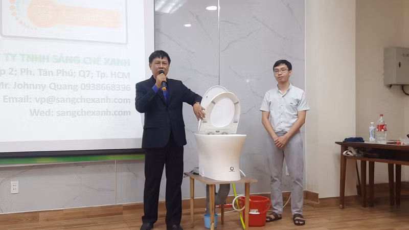 Ông Nguyễn Văn Nam (bên trái ảnh) thuyết trình về nguyên lý hoạt động của sáng chế hệ thống cơ-điện điều khiển bồn cầu xả nước.