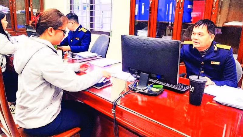 Công chức ngành thuế hướng dẫn người dân kê khai nộp thuế vào ngân sách nhà nước. (Ảnh HOÀI AN)