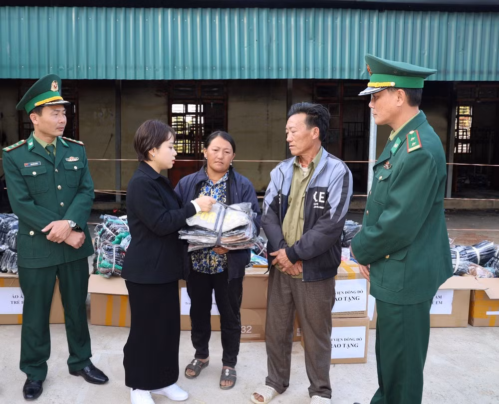Cán bộ Đồn Biên phòng Nậm Lạnh phối hợp với đoàn thiện nguyện trao quà cho gia đình em học sinh gặp nạn trong vụ cháy.