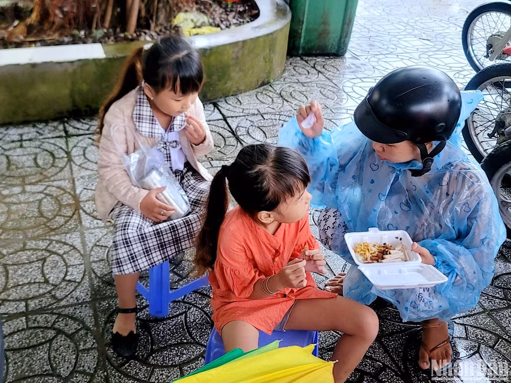 Một phụ huynh tại thành phố Cà Mau tranh thủ cho con ăn sáng ngay tại sân trường để kịp giờ khai giảng năm học mới.