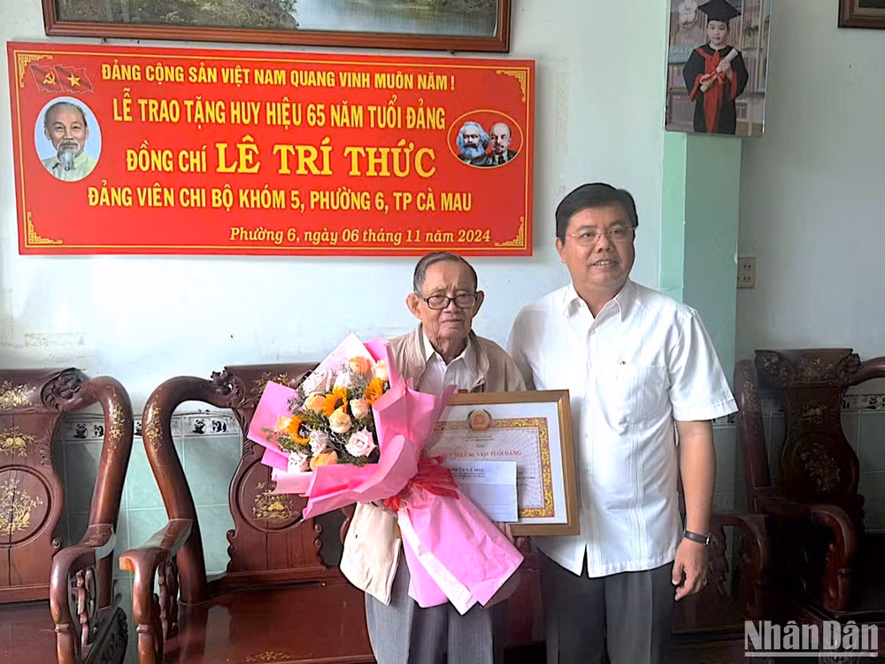 Bí thư Tỉnh ủy Cà Mau Nguyễn Tiến Hải trao tặng Huy hiệu 65 năm tuổi Đảng và tặng hoa chúc mừng đảng viên Lê Trí Thức.