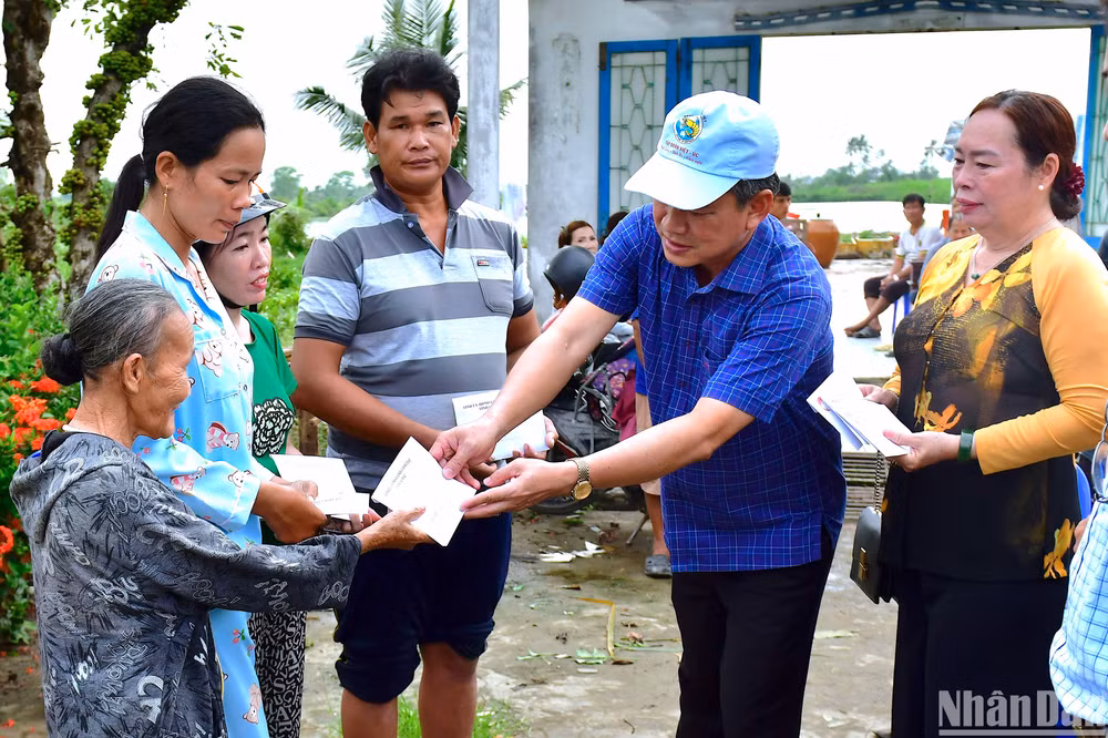Phó Chủ tịch Mặt trận Tổ quốc tỉnh Cà Mau (đội nón) trao hỗ trợ bước đầu cho hộ dân huyện U Minh có nhà bị hư hỏng do dông lốc.