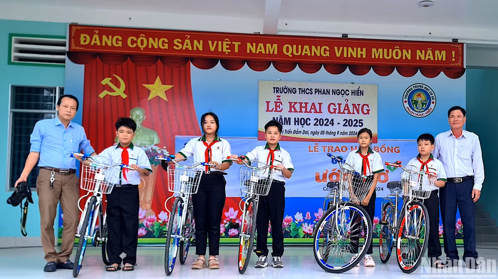 Đại diện Báo Nhân Dân tại Cà Mau (bìa trái) trao hỗ trợ xe đạp tại huyện Đầm Dơi (tỉnh Cà Mau).