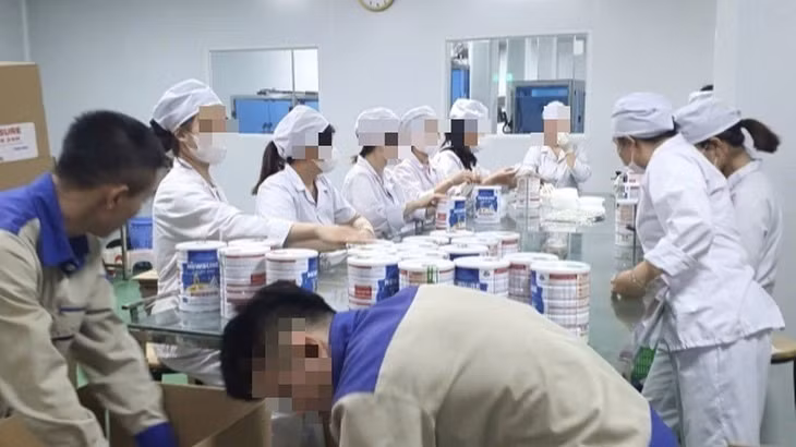 Công nhân đóng hộp thành phẩm tại cơ sở sản xuất sữa bột giả quy mô lớn vừa bị Công an thành phố Hà Nội triệt phá. (Ảnh: Báo Công an nhân dân)