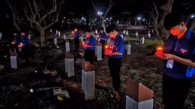 Các đoàn viên thanh niên thắp nến tri ân tại phần mộ các anh hùng liệt sĩ. (Ảnh: VŨ TÂN)