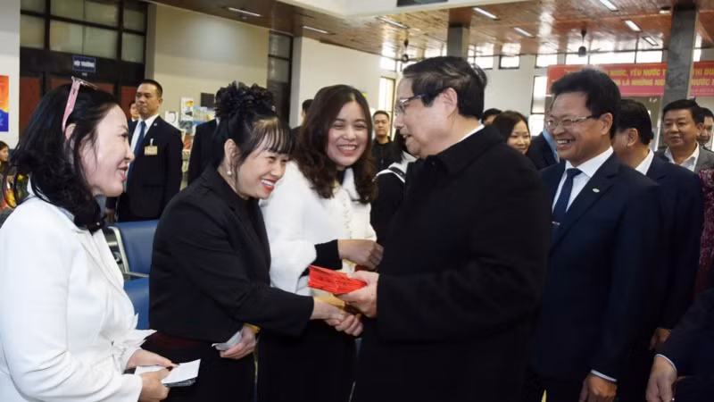 Thủ tướng Phạm Minh Chính mừng tuổi cho các hành khách đang chờ tàu tại ga Hà Nội. (Ảnh: TRẦN HẢI)