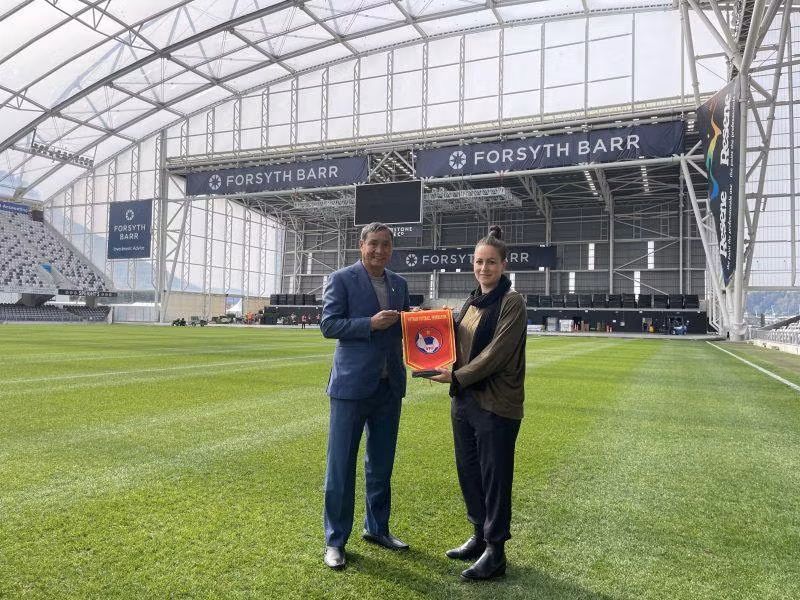 Huấn luyện viên Mai Đức Chung trao cờ lưu niệm cho đại diện sân vận động Dunedin (Yorsyth Barr). (Ảnh: VFF)