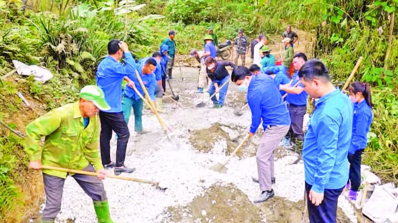 Cán bộ, hội viên các tổ chức giúp nhân dân thôn Bản Lằn trộn bê-tông làm đường giao thông thôn, bản.