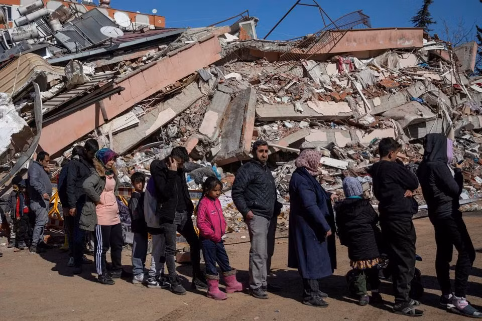 Người dân Thổ Nhĩ Kỳ xếp hàng bên đống đổ nát của trận động đất để nhận thực phẩm miễn phí. (Ảnh: Reuters) Người dân Thổ Nhĩ Kỳ xếp hàng bên đống đổ nát của trận động đất để nhận thực phẩm miễn phí. (Ảnh: Reuters)