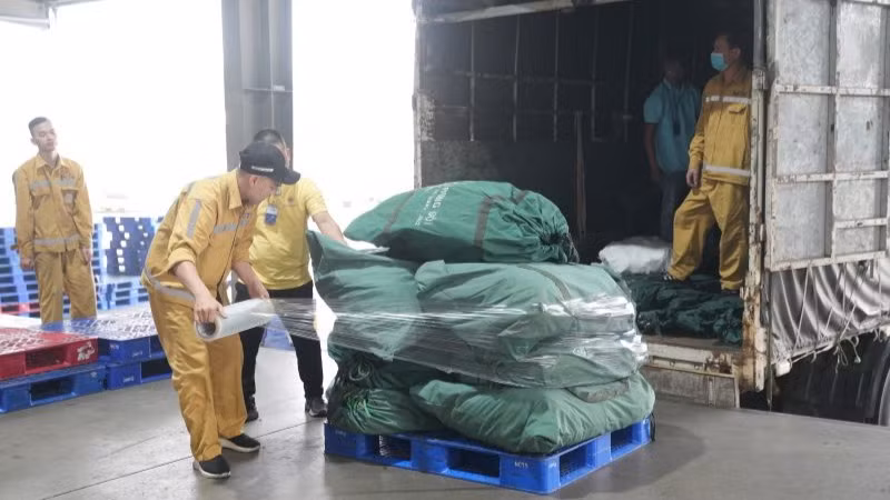 Nhân viên kho hàng dỡ các thùng hàng cứu trợ từ xe tải xuống, bảo đảm rằng mọi thứ được xử lý một cách nhanh chóng và chính xác.