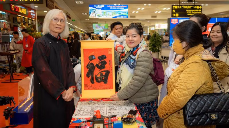 Tặng chữ thư pháp cho hành khách đi tàu bay.