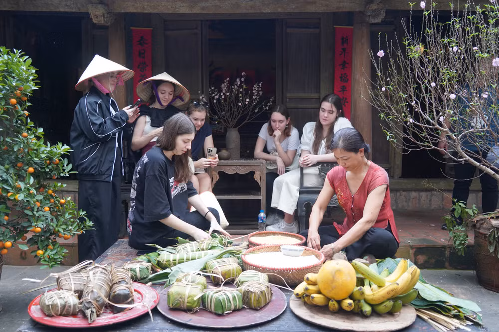Các vị khách quốc tế trải nghiệm gói bánh chưng.
