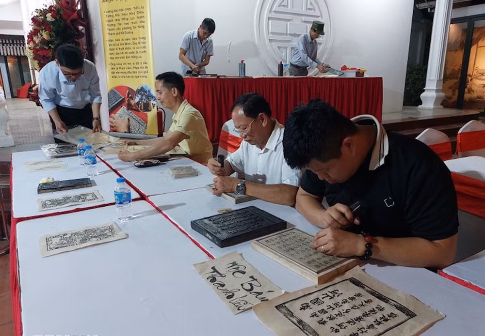 Các nghệ nhân làng nghề khắc mộc bản Thanh Liễu (Hải Dương) trình diễn kỹ thuật khắc tranh, sách để in trên giấy dó.