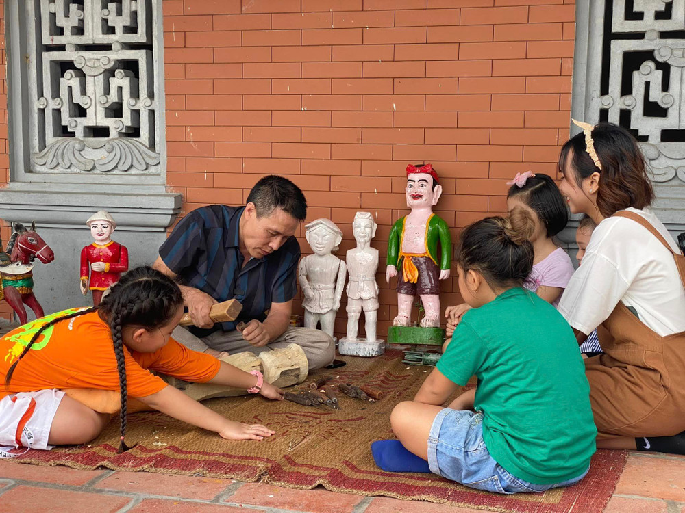 Nghệ nhân phường rối nước Đào Thục giới thiệu với khách du lịch về nghệ thuật tạo hình quân rối.