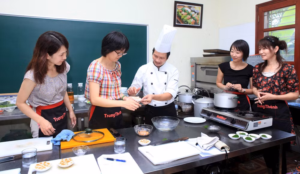 Giáo viên Trường trung cấp Kinh tế-Du lịch Hoa Sữa dạy khách nước ngoài làm món ăn truyền thống của Việt Nam. Ảnh: Anh An