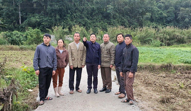 Ông Nông Văn Hòa (đứng giữa) giới thiệu với người dân về hiệu quả bê-tông hóa đường giao thông nông thôn.