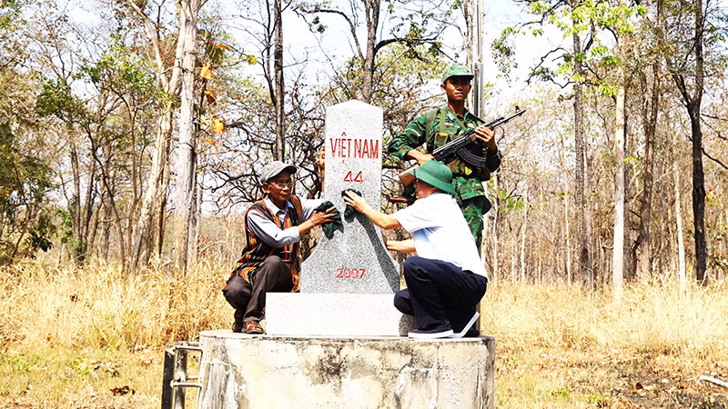 Già làng, người có uy tín xã biên giới Krông Na, huyện Buôn Ðôn (Ðắk Lắk) lau chùi cột mốc chủ quyền biên giới quốc gia trên địa bàn. 