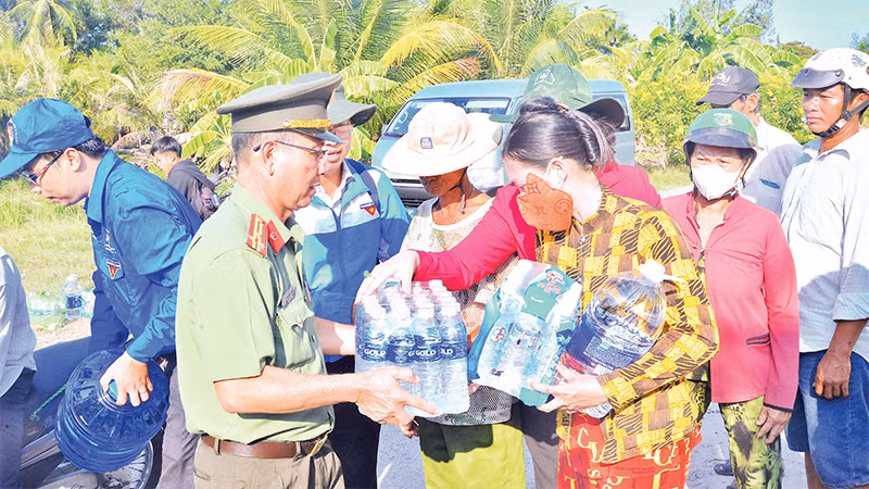 Cán bộ, chiến sĩ Phòng Công tác đảng và công tác chính trị (Công an tỉnh Cà Mau) vận chuyển, cung cấp nước sinh hoạt miễn phí cho người dân xã Khánh Bình Ðông, huyện Trần Văn Thời, tỉnh Cà Mau. 