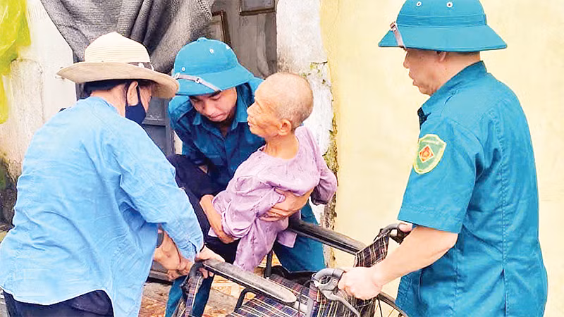 Chính quyền địa phương giúp đỡ những người già yếu, tàn tật sơ tán khỏi mưa lũ. 