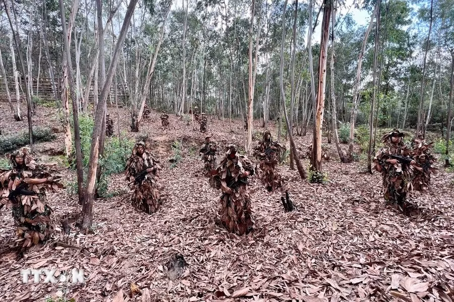 Chiến sĩ Cảnh sát cơ động chống khủng bố thực hiện bài tập nguỵ trang dưới lớp lá khô, tiếp cận đối tượng một khoảng cách gần nhất mà không bị phát hiện. (Ảnh: TTXVN)