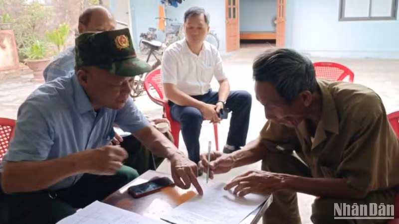 Tổ công tác thôn Trung Lập (xã Vũ Hội, huyện Vũ Thư) hướng dẫn người dân lấy ý kiến sắp xếp bộ máy hành chính cấp tỉnh, cấp xã năm 2025 thông qua mẫu phiếu in sẵn.