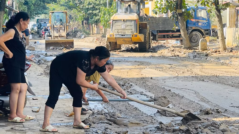 Nhân dân phường Nguyễn Phúc tham gia cùng Công ty cổ phần Xây dựng giao thông Yên Bái dọn bùn trên trục đường đi huyện Trấn Yên. (Ảnh: THANH SƠN)