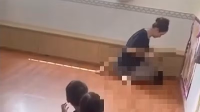 Người phụ nữ ngồi trên bụng cháu bé (Ảnh cắt từ clip) 