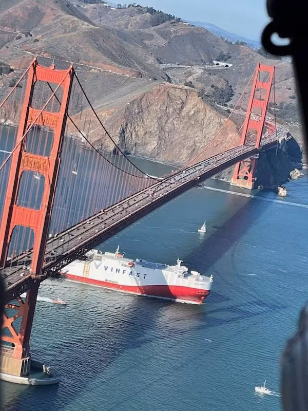 Chiếc tàu chở lô xe VinFast qua cầu Cổng Vàng biểu tượng.