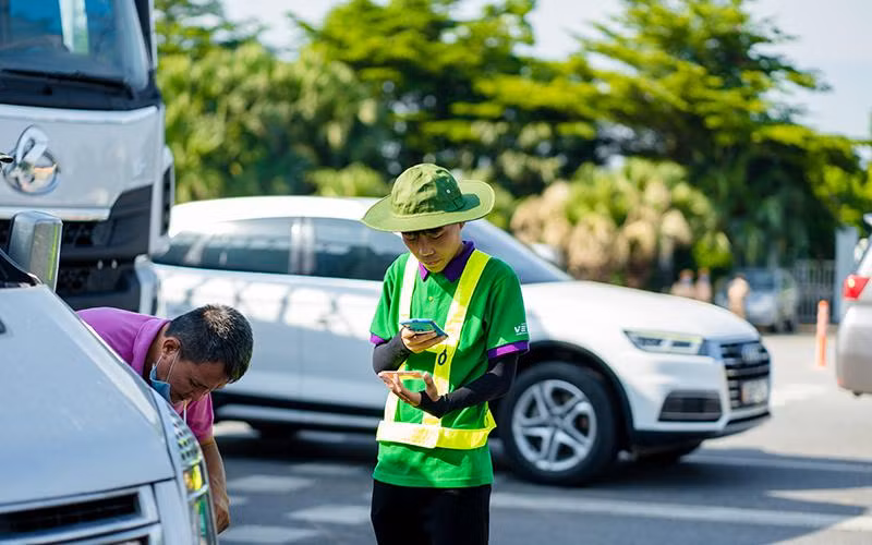 Nhân viên cung cấp dịch vụ ETC hướng dẫn, hỗ trợ khách hàng dán thẻ, nạp tiền vào tài khoản.