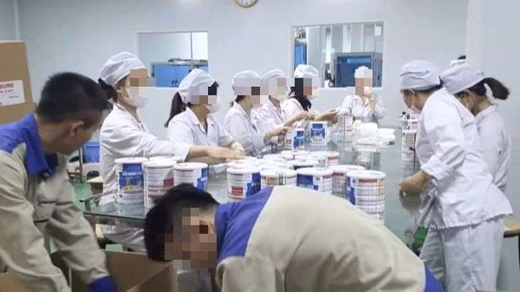 Công nhân đóng hộp thành phẩm tại cơ sở sản xuất sữa bột giả quy mô lớn vừa bị Công an thành phố Hà Nội triệt phá. (Ảnh: Báo Công an nhân dân) 