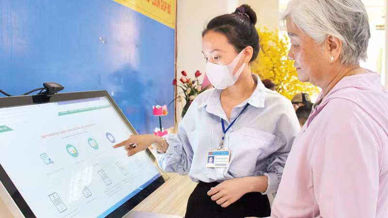 Cán bộ phường Bến Nghé, Quận 1 hướng dẫn người dân thực hiện đăng ký hồ sơ trực tuyến. (Ảnh: THẾ ANH)