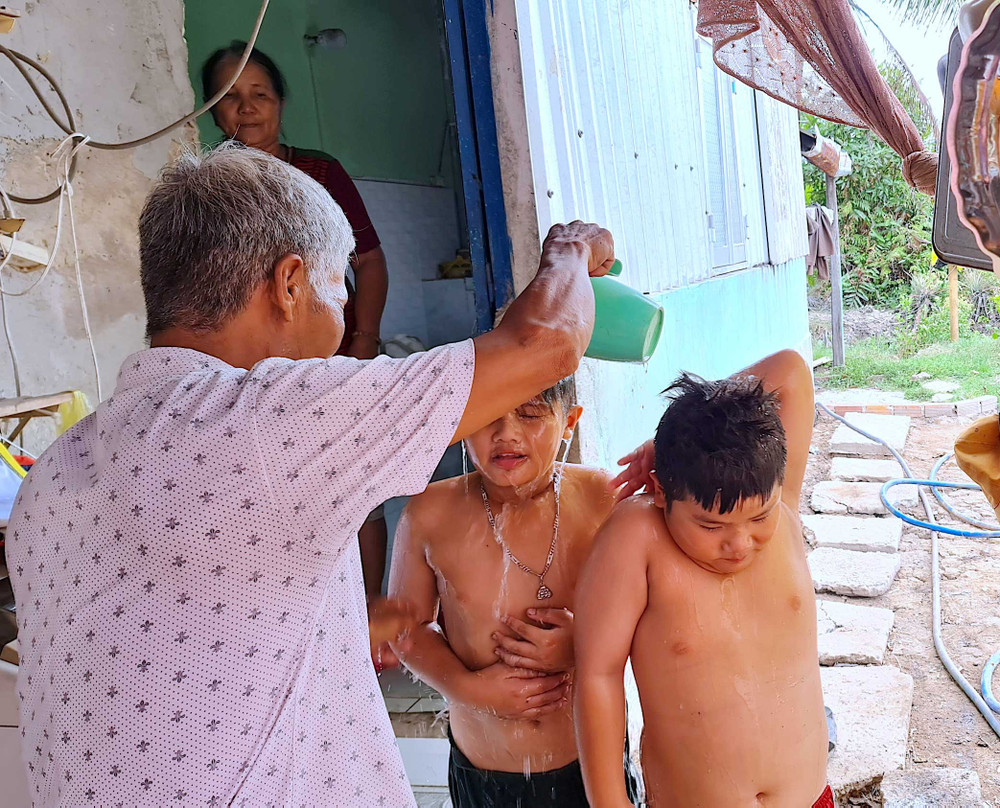 Bé Tuấn Khải, Tuấn Quy (ấp Minh Hà B) được người nhà dội rửa lại bằng ít nước ngọt sau khi tắm nước mặn dưới vuông tôm.