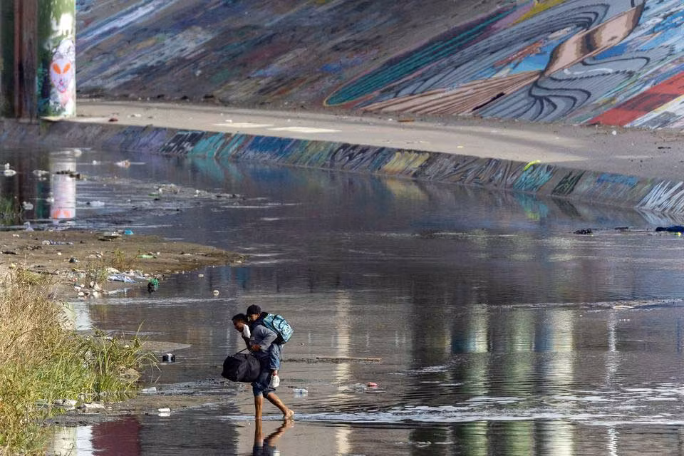 Người di cư vượt biên từ Mexico qua sông Rio Bravo vào Mỹ. (Ảnh REUTERS)