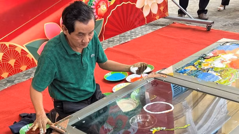 Họa sĩ Đoàn Việt Tiến biểu diễn vẽ tranh ngược trên kính.