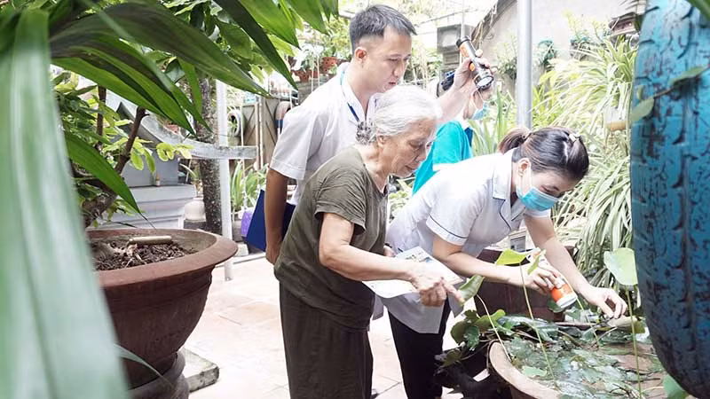 Cán bộ y tế hướng dẫn người dân trên địa bàn quận Long Biên kiểm tra và diệt bọ gậy. (Ảnh DUY TUÂN)