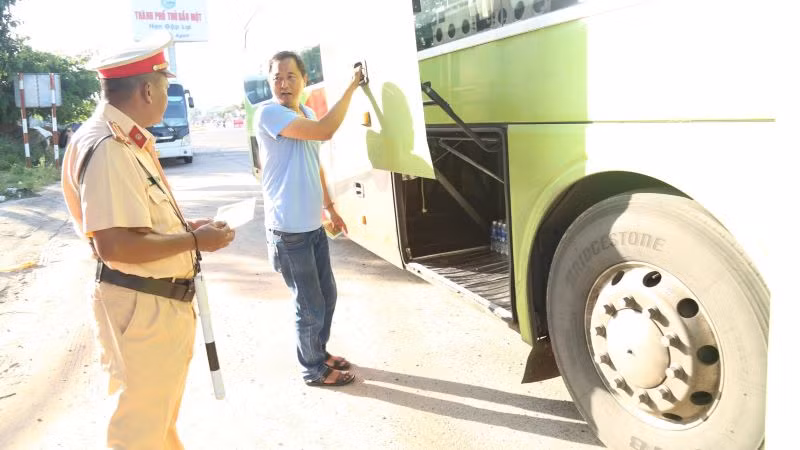 Cảnh sát giao thông đang kiểm tra một xe ô-tô kinh doanh vận tải hành khách.