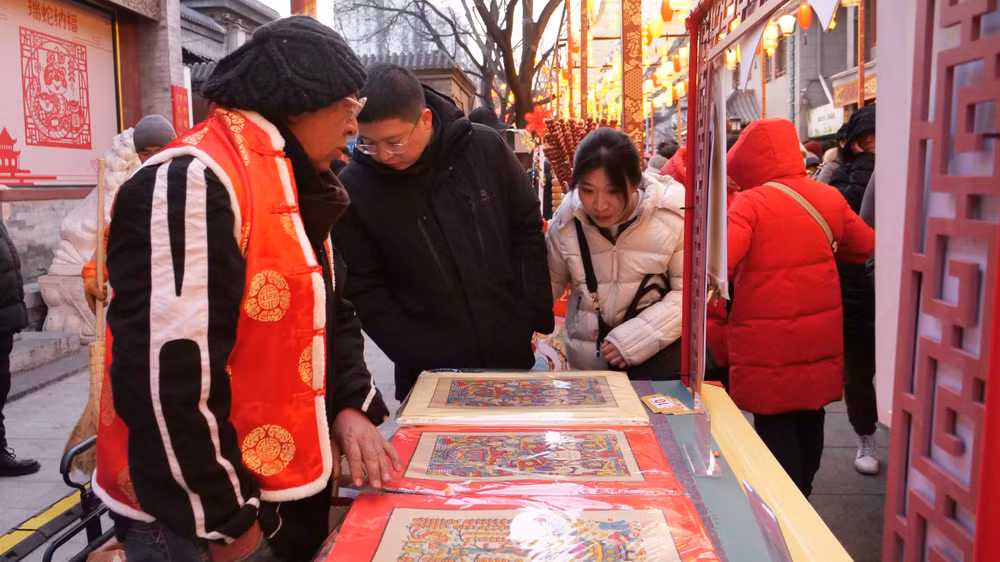 Đôi bạn trẻ ngắm lựa tranh Tết truyền thống ở phố đi bộ của thủ đô Bắc Kinh ngày mùng 3 Tết.