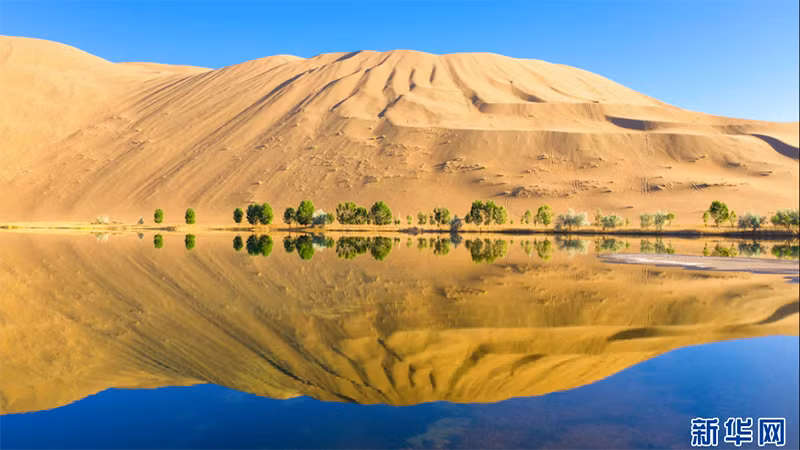 Núi cát soi bóng xuống hồ nước trên sa mạc Badain Jaran. (Ảnh: Tân Hoa xã)