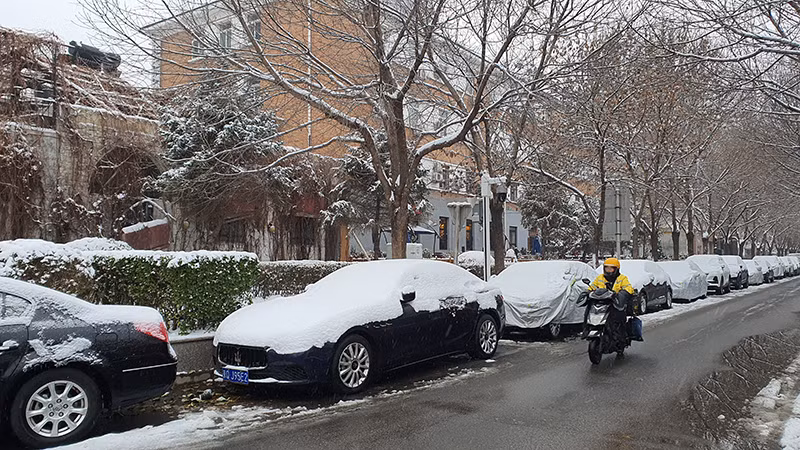 Một người dân di chuyển bằng xe đạp điện trong gió tuyết mạnh.