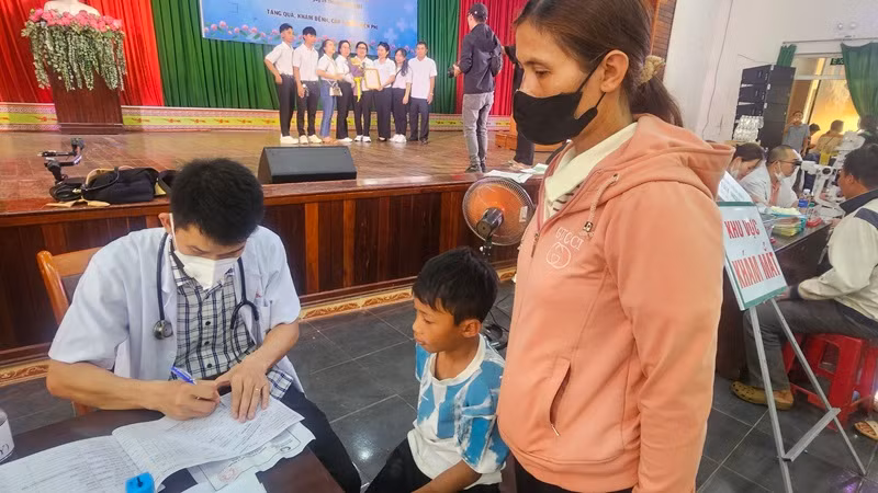 Một gia đình có hoàn cảnh khó khăn đưa con đến đăng ký khám bệnh miễn phí.