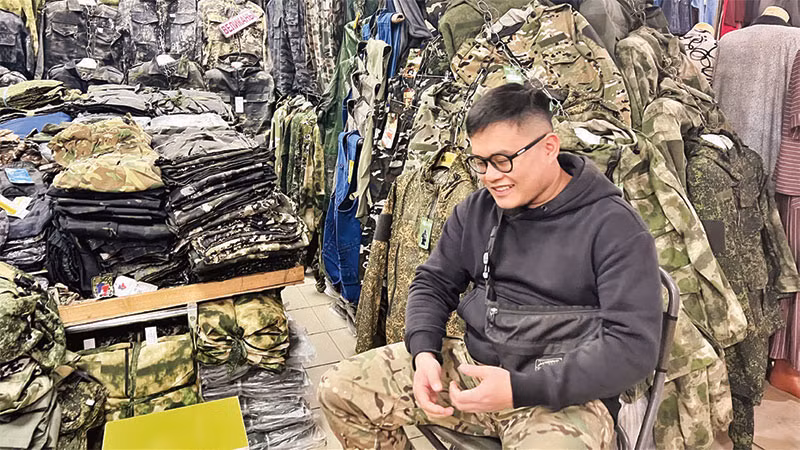 Thành ngồi trước gian hàng của mình trong chợ.