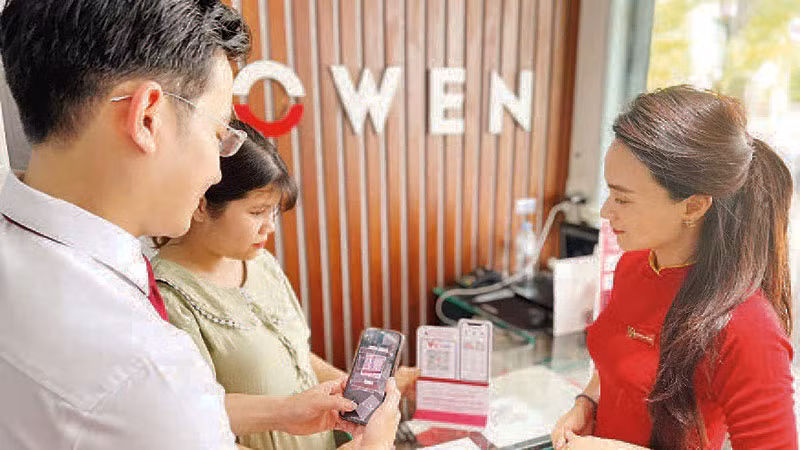 Nhân viên ngân hàng hướng dẫn khách hàng thanh toán không dùng tiền mặt. (Ảnh: CTV)