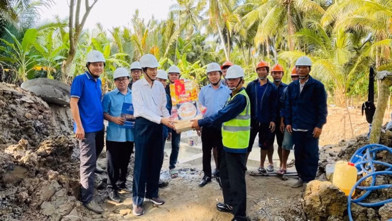 Thành viên Hội đồng thành viên EVNSPC Lê Xuân Hải (áo trắng) tặng quà động viên lực lượng lao động thi công dự án trên địa bàn tỉnh Bến Tre ngày 26 Tết.