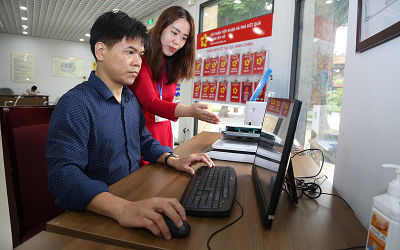 Cán bộ bộ phận một cửa Ủy ban nhân dân quận Tây Hồ hướng dẫn người dân làm thủ tục hành chính.