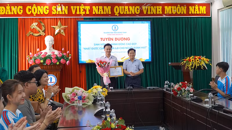 Đại diện lãnh đạo Trường Đại học Đồng Tháp Cao Dao Thép trao giấy khen và tiền thưởng cho em Nguyễn Minh Toàn. (Ảnh: HỮU NGHĨA)