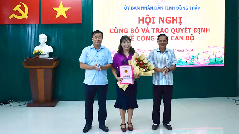 Phó Chủ tịch Ủy ban nhân dân tỉnh Đồng Tháp Nguyễn Phước Thiện (bìa trái) trao quyết định, Giám đốc Sở Nội vụ Phan Hữu Phước tặng hoa chúc mừng nhà báo Ngô Thị Ngọc Hạnh.